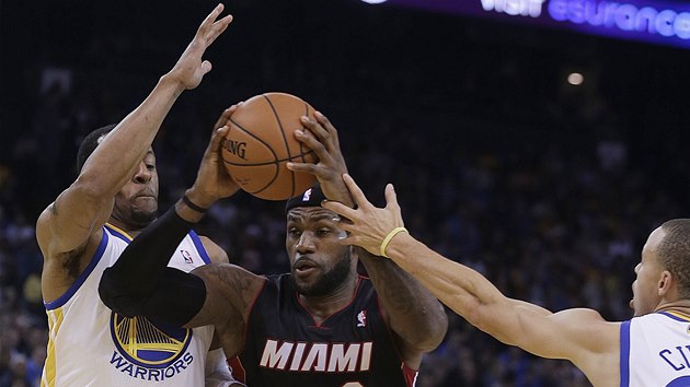 LeBron James z Miami si razí cestu mezi hrái Golden State Warriors. Vlevo je