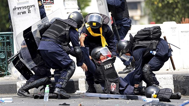 Thajt policist se sna pomoci svmu kolegovi, kterho zranil vbuch nloe (Bangkok, 18. nora 2014).