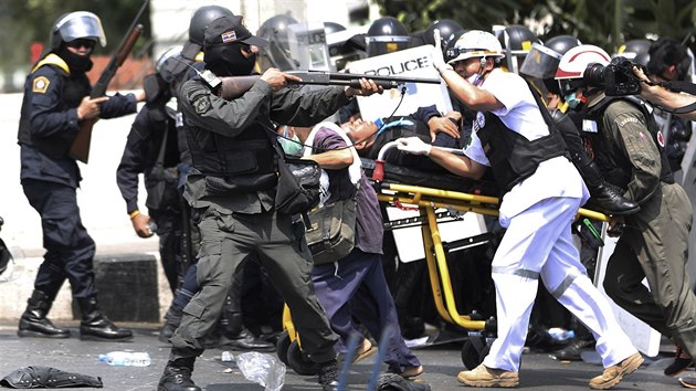 Zdravotnci odnej zrannho policistu, zatmco jeho kolegov kontroluj situaci gumovmi projektily (Bangkok, 18. nora 2014)