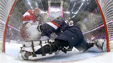 Ruský centr Jevgenij Malkin padá po tvrdém zákroku na amerického gólmana...