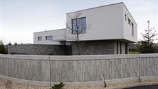 Zaoblený plot z pohledového betonu vizuálně koresponduje s šedobílou hmotou
