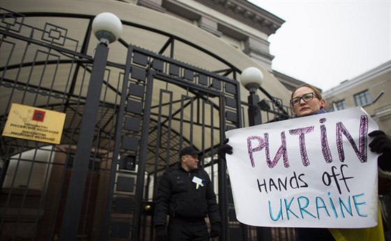 Žena s transparentem "Putine ruce pryč od Ukrajiny" během protestu před ruskou