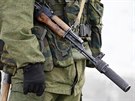 Ruský ozbrojenec hlídkuje u brány ukrajinské vojenské základny v Perevalnoje u...