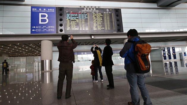 Lidé na letišti v Pekingu si fotí informační tabuli s údaji o problémech Boeingu 777-200  společnosti Malaysia Airlines z Kuala Lumpur.