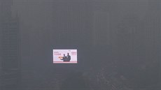 Ve smogem zahaleném �ínském m�st� �en-jang zá�í jen elektronický billboard na...
