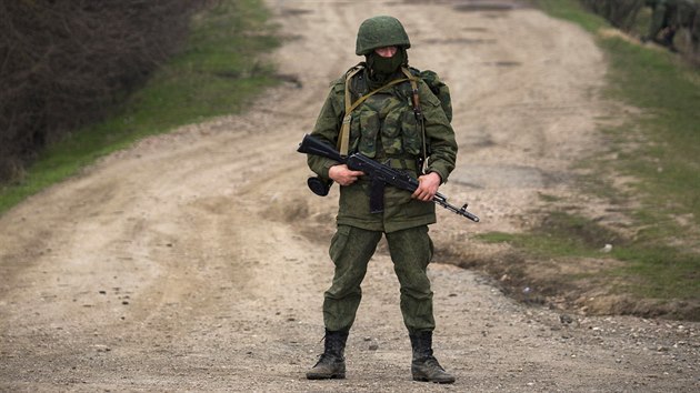 Ozbrojenec hlídá nedaleko základny ukrajinských vojáků u Perevalnoje. Podle agentury Reuters patří k ruským jednotkám, byť nemá na sobě žádná označení. (12. března 2014)