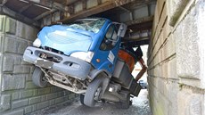 Řidič nákladního auta s bagrem na korbě se nevešel pod viadukt v Nebanicích.