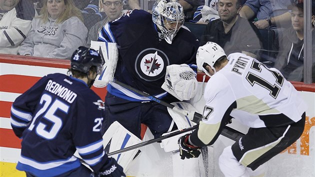 Brank Ondej Pavelec z Winnipegu bojuje u mantinelu s  Taylorem Pyattem z Pittbsurghu. Pihl Zach Redmond.