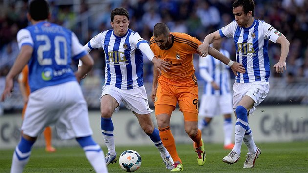 Karim Benzema z Realu Madrid (v oranovm) se prodr mezi dvma strci ze San Sebastianu. Nalevo je Gorka Elustondo, vpravo Mikel Gonzlez.
