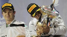 Nico Rosberg (vlevo) se dívá, jak Lewis Hamilton líba trofej pro vítze Velké