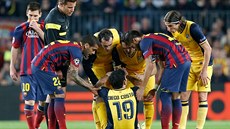 Hráči Barcelony a Atlétika Madrid (ve žlutém) se sklánějí nad zraněným Diegem...