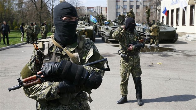Neoznaen ozbrojenci v centru Slavjansku. Na jejich transportrech je vidt rusk vlajka a zstava vsadk, kterou pouvaj jak rut, tak ukrajint paragni (16. dubna 2014)