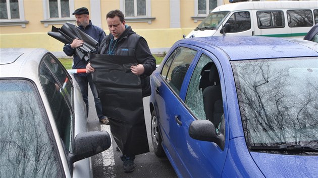 Policisté kontrolují automobily poničené při noční střelbě v Krnově. Poškozená místa následně přikrývali plachtami.