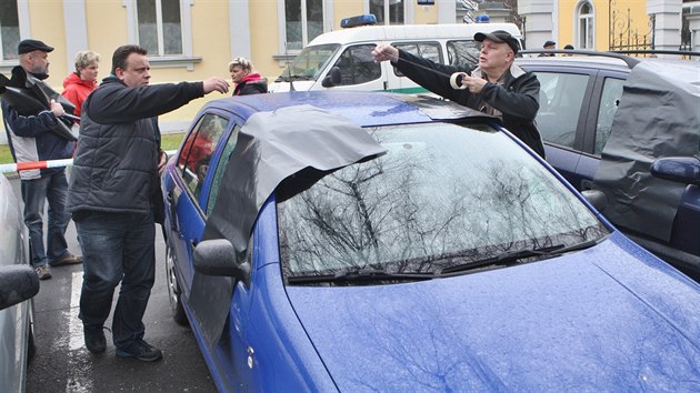 Policisté kontrolují automobily poničené při noční střelbě v Krnově. Poškozená místa následně přikrývali plachtami.