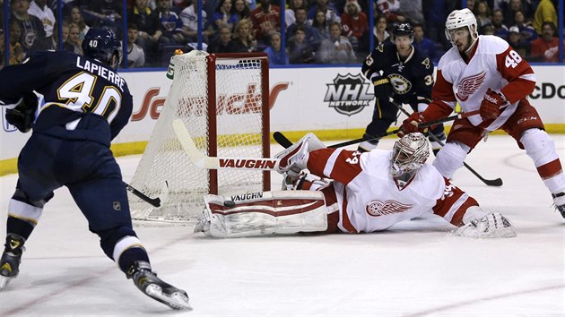 Brank Petr Mrzek z Detroitu likviduje stelu Maxima Lapierrea (vlevo) ze St. Louis.  Jak to dopadne sleduj obrnce Red Wings Ryan Sproul (vpravo)  a' Jordan Leopold ze St. Louis (vzadu).