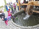 U mlýnského kola se z vody vynouje vodník.
