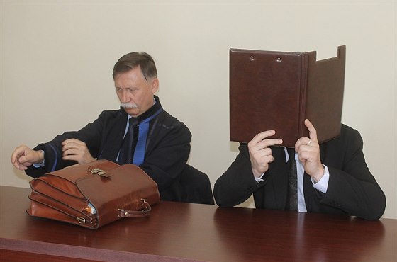 Obžalovaný Miroslav Zeman si u soudu schovával obličej za desky s dokumenty.