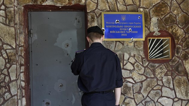 Ukrajinsk vojk si prohl stopy po kulkch na vchodovch dvech zkladny sil ministerstva vnitra v Luhansku (20. kvtna 2014).