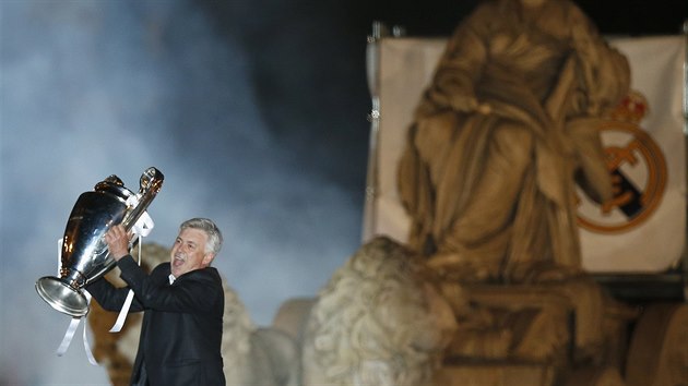 Trenr Carlo Ancelotti ukazuje trofej z Ligy mistr rozjaenm fanoukm Realu Madrid. Za nm socha bohyn Cybele.