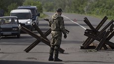 Proruský ozbrojenec stojí na silniním zátarasu nedaleko Slavjansku na trase do...
