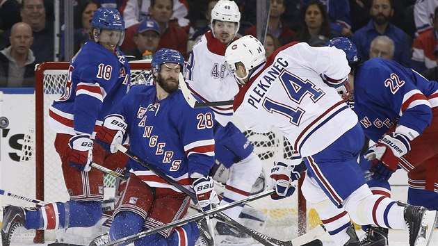 Tom Plekanec (druh zleva) z Montrealu se sna prostelit hradbu tl ped brankou New York Rangers.