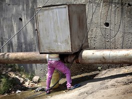 SBÍRÁNÍ VODY. Malý kluk se snaí nabrat vodu z prasklého potrubí v indickém...