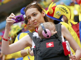 A fan of Switzerland carrying a child, takes a photo before their 2014 World...