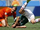 Mexický záloník Hector Herrera padá na zem po zákroku nizozemského obránce...