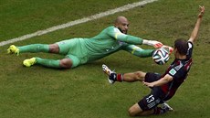 Americký branká Tim Howard zasahuje ped nmeckým útoníkem Thomasem Müllerem.