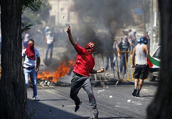 Palestinec hází kámeny na izraelské policisty bhem pohbu chlapce uneseného z...