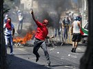 Palestinec hází kámeny na izraelské policisty bhem pohbu chlapce uneseného z...