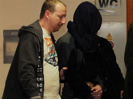 Michal Krná obalovaný z vrady Romana Housky zstává ve vazb. Na snímku ho policisté pivádjí maskovaného pytlem na hlav.