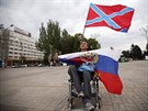Mu drí vlajku Ruska a Novoruska pi demonstraci na Leninov námstí v centru...