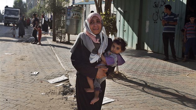 ena z msta Gaza pláe, zatímco lidé opoutjí své domovy poté, co je ped...