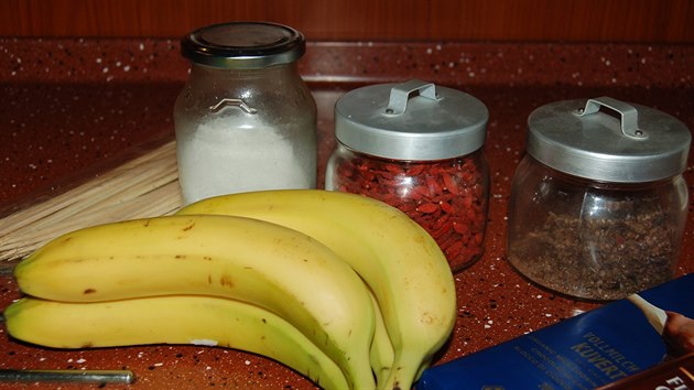 Potřebujete zralé čerstvé banány, kvalitní čokoládu (na snímku hořká i mléčná, použili jsme hořkou), kokosový tuk a cokoliv na obalení. Například (sklenice zleva) strouhaný kokos, kustovnici nebo čokoládové vločky.  