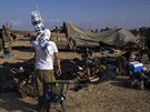 Izraelský voják si bere modlitební ál, zatímco jeho druzi odpoívají nedaleko...