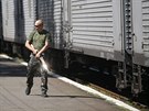 Ozbrojený proruský separatista hlídkuje u vlaku, ve kterém jsou uloeny ostatky...