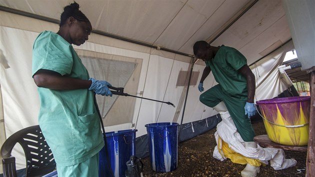 len tmu Lka bez hranic v sierraleonskm Kailahunu si svlk ochrann oblek po pchodu z izolan jednotky, zatmco ho jeho kolegyn dezinfikuje (20. ervence 2014).