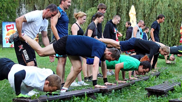 Boxer René Blažejovský vede cvičení pro skupinu mladých lidí. Využívají rekvizity v parku a letním kině.