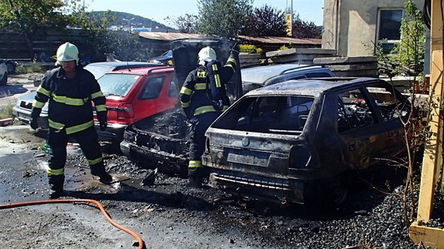 Hasiči dokončují zásah u požáru čtyř osobních aut v Harnicích. Při požáru se zranil jeden člověk (18. 8. 2014).