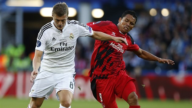 SOUBOJ. Toni Kroos z Realu Madrid (vlevo) vede m v utkn o Superpohr, atakuje ho  Carlos Bacca ze Sevilly.  