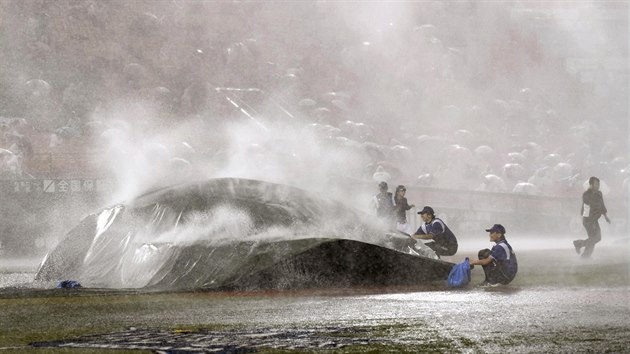 Poadatel se sna rychle zakrt ped detm plochu baseballovho stadionu v Jokoham. Japonsko v nedli 10. srpna 2014 zashla tropick boue Halong.