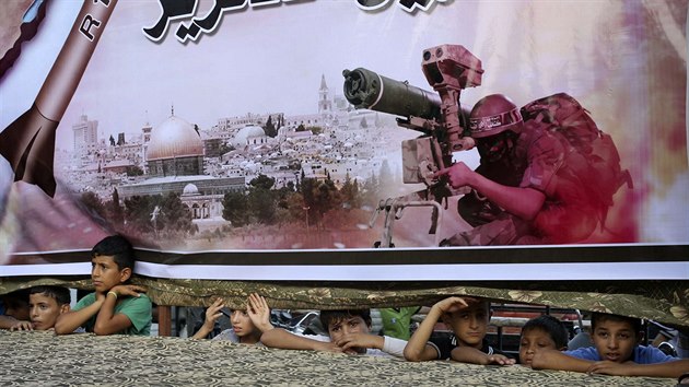 Palestinsk dti se koukaj pod plaktem podporujc palestinsk hnut v Rafhu (17. srpna 2014).
