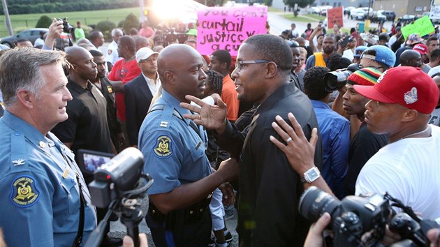 Prezident ernch prvnk za spravedlnost Malik Shabazz (v brlch) se rozhodl vyjednat ve Fergusonu klid. Vlevo poruk Ron Replogle, uprosted velitel mstn policie Ron Johson.