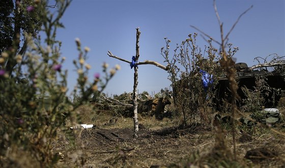 Hrob ukrajinského vojáka mezi troskami bojové techniky u vesnice Osykove na...