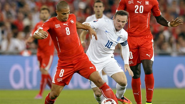 Kapitn anglick reprezentace Wayne Rooney atakuje vcarskho fotbalistu Goekhana Inlera. 