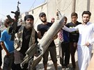Bojovník Islámského státu ukazuje trosky syrského vládního letounu, které...