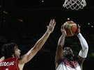 Americký basketbalista Kyrie Irving (u míe) proniká k srbskému koi kolem...