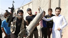 Bojovník Islámského státu ukazuje trosky syrského vládního letounu, které...