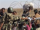 Turecký voják podává vodu kurdským uprchlík utíkajícím ped Islámským státem...